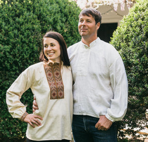Woman and man standing outside with hedges behind them.  Woman is wearing embroiders View B and man is wearing plain white View B.  The are standing side by side with arms around eachother.