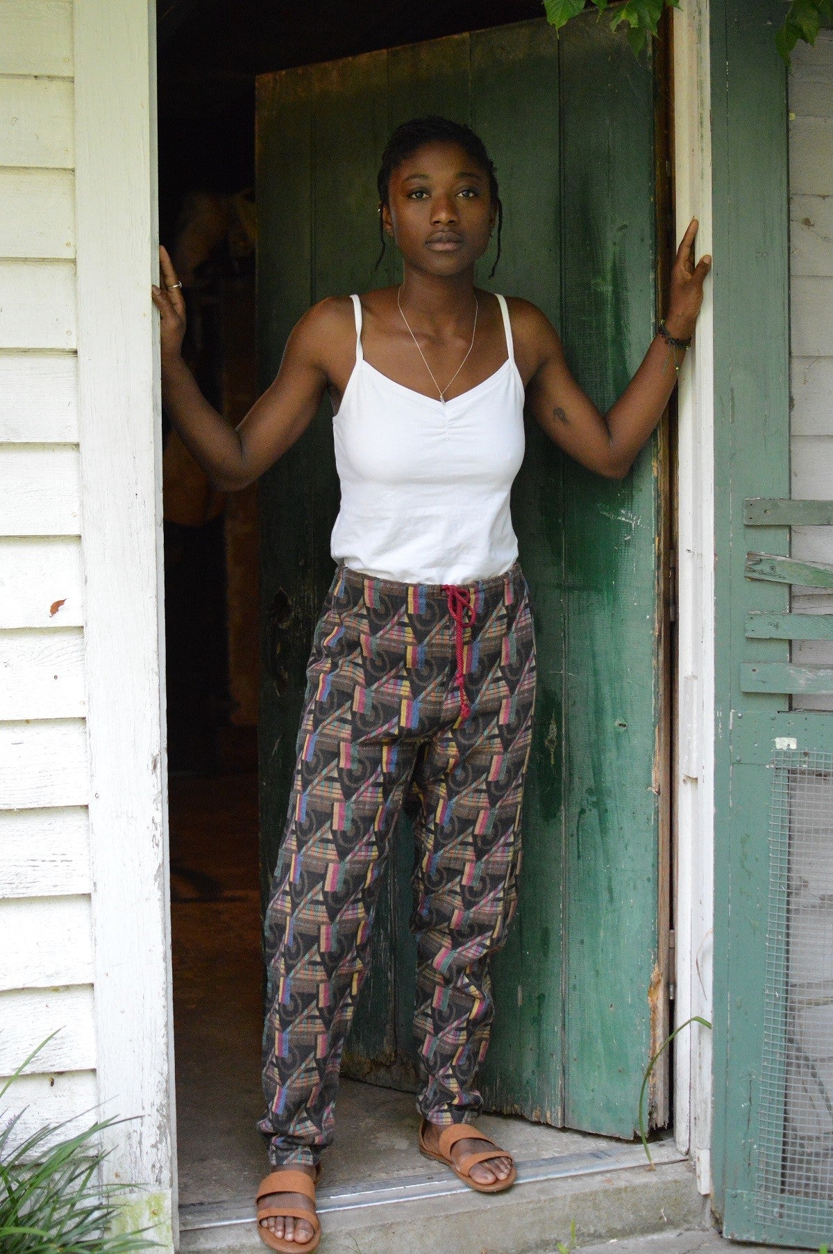 Young African American woman standing in a doorway wearing 119 Sarouelle pants view B (African Pants)