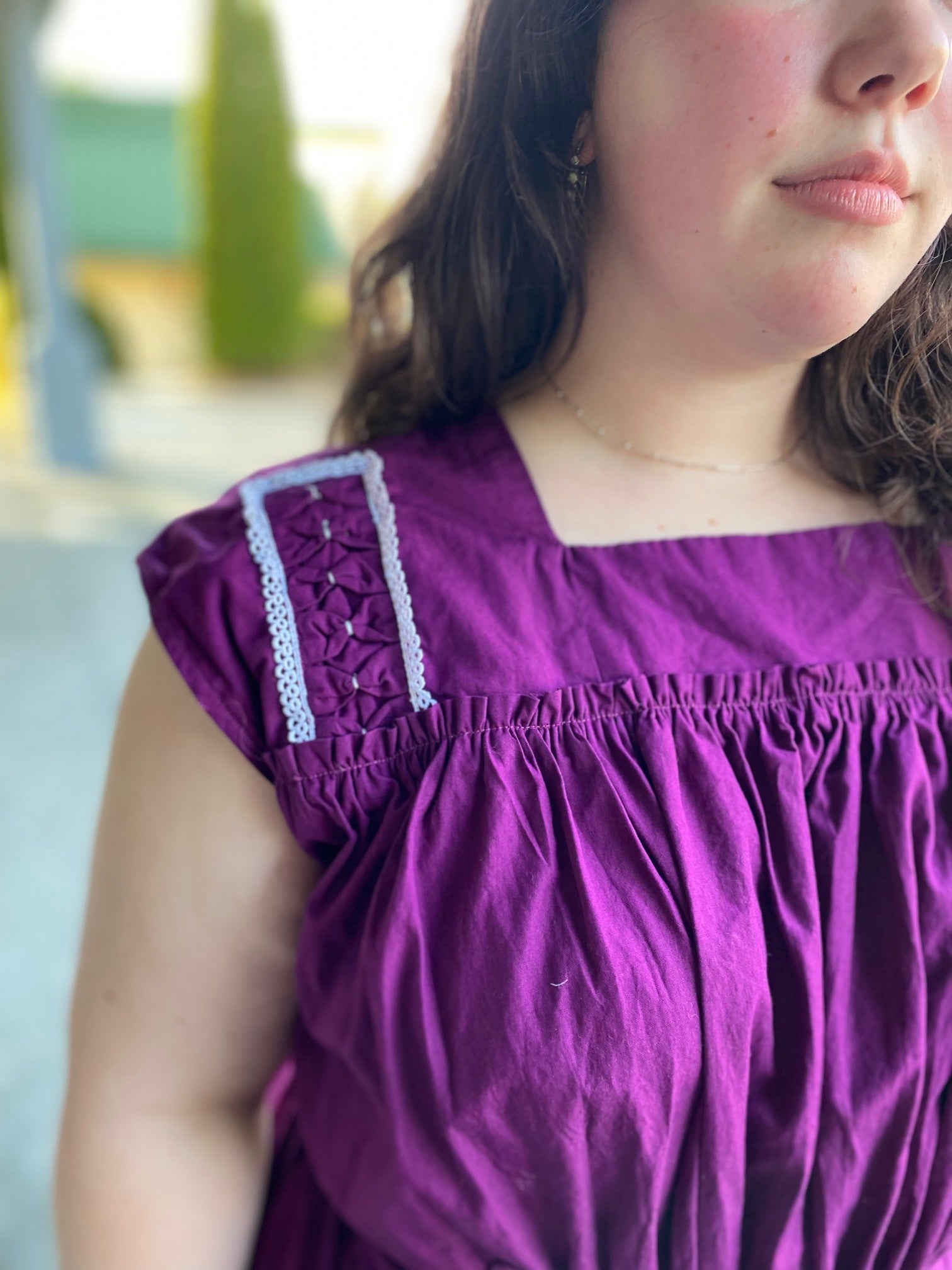 Young woman wearing a purple sleeveless dress with some embellished shoulder yoke.