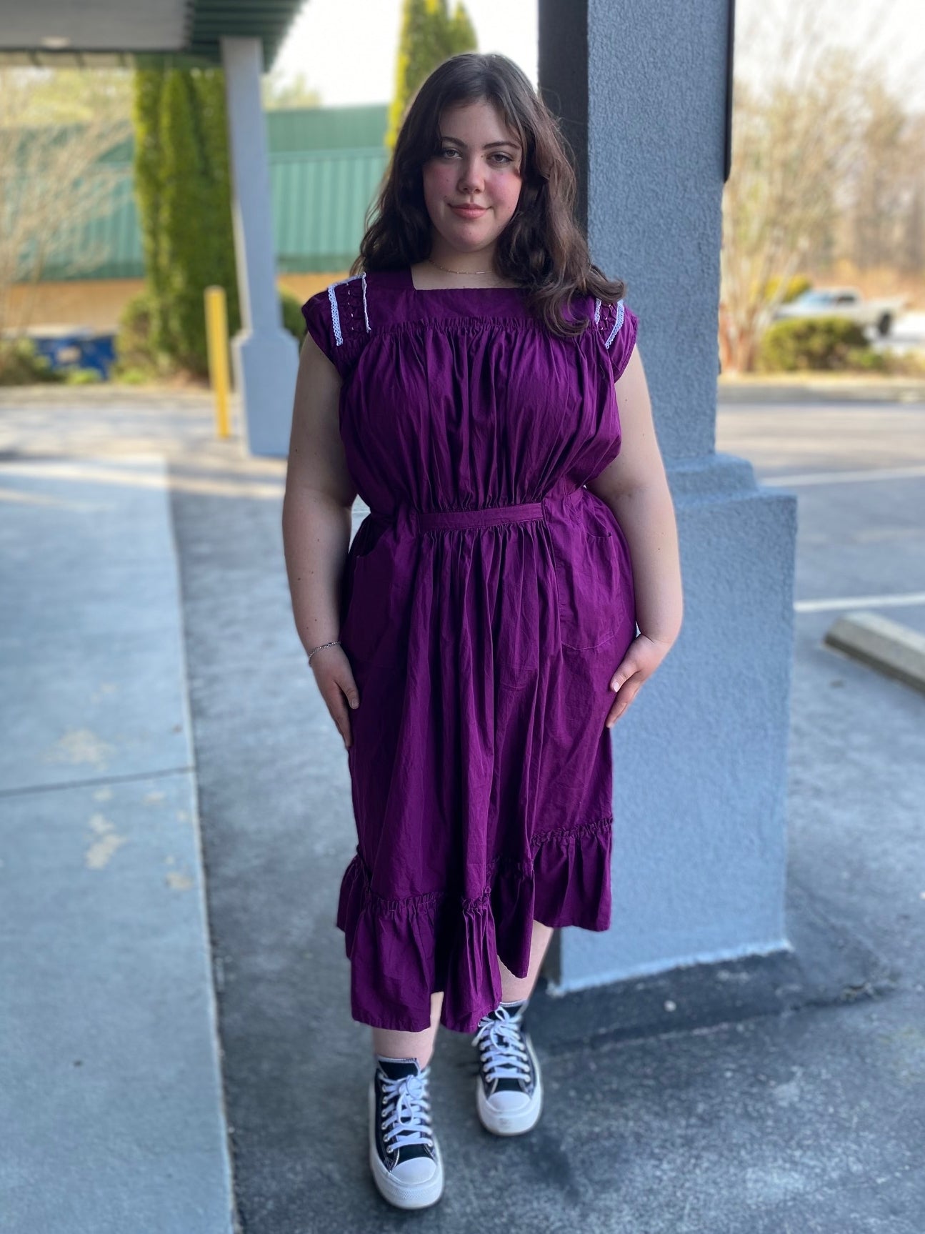 Young woman wearing a purple sleeveless dress with some embellished shoulder yoke.