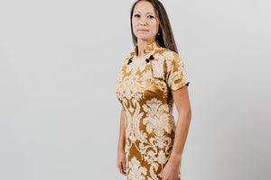 Close up of woman wearing a knee-length gold brocade cheongsam