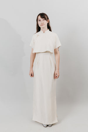 Woman wearing a white cheongsam standing in front of a white background.