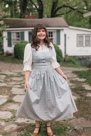 Woman walking on stone path wearing Dirndl View A.  Dress is light blue.