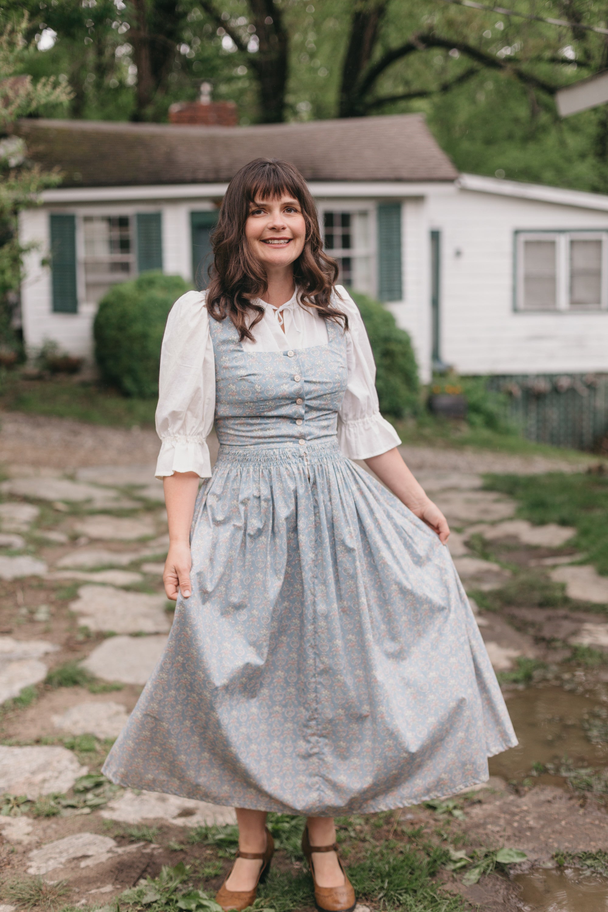 Woman walking on stone path wearing Dirndl View A.  Dress is light blue.