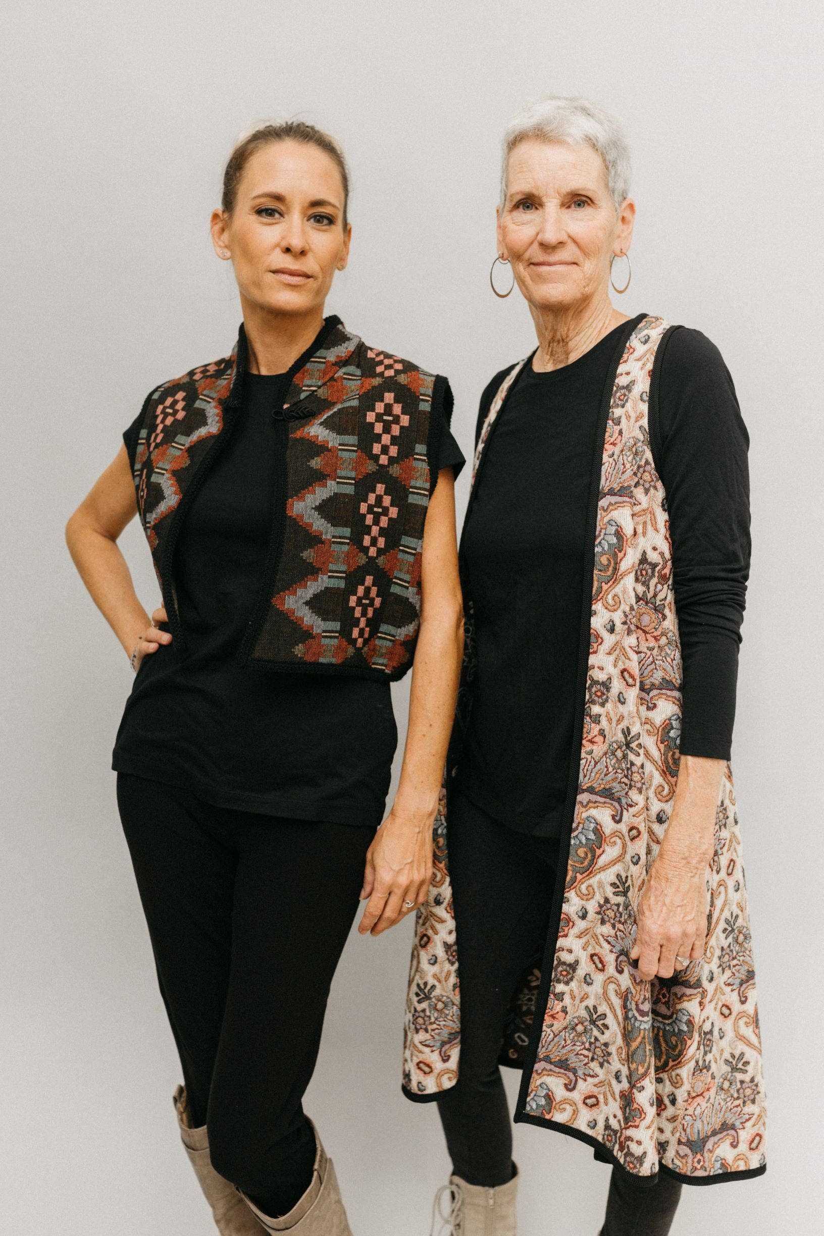 Photo of two women standing side by side in two Views of Greek Vests.  Woman on left is wearing Short Greek Vest and woman on right wears Long Greek Vest.