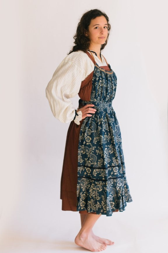 Model wearing Russian settlers outfit.  Blouse is worn under jumper and apron is worn over the jumper.