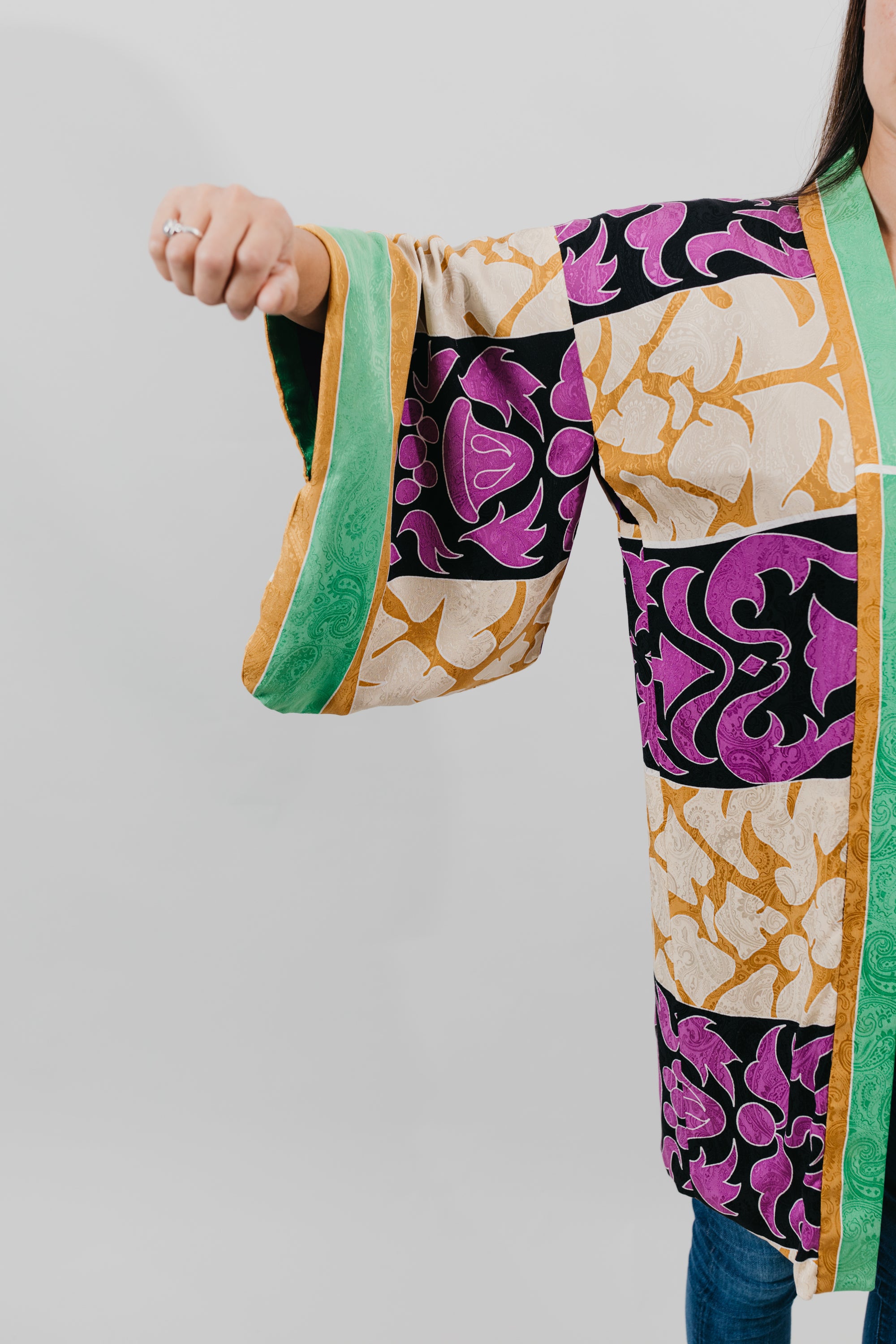 Asian woman wearing a purple, black, green, and gold printed Haori - close up of the sleeve.