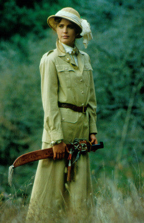 Woman standing in tall grass wearing 130 Jacket and 209 Walking Skirt.  Model holds an machete in hands and wears a sun hat.