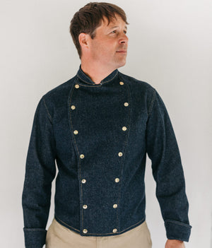 Man wearing a dark denim Belgian military chef's coat. white background.
