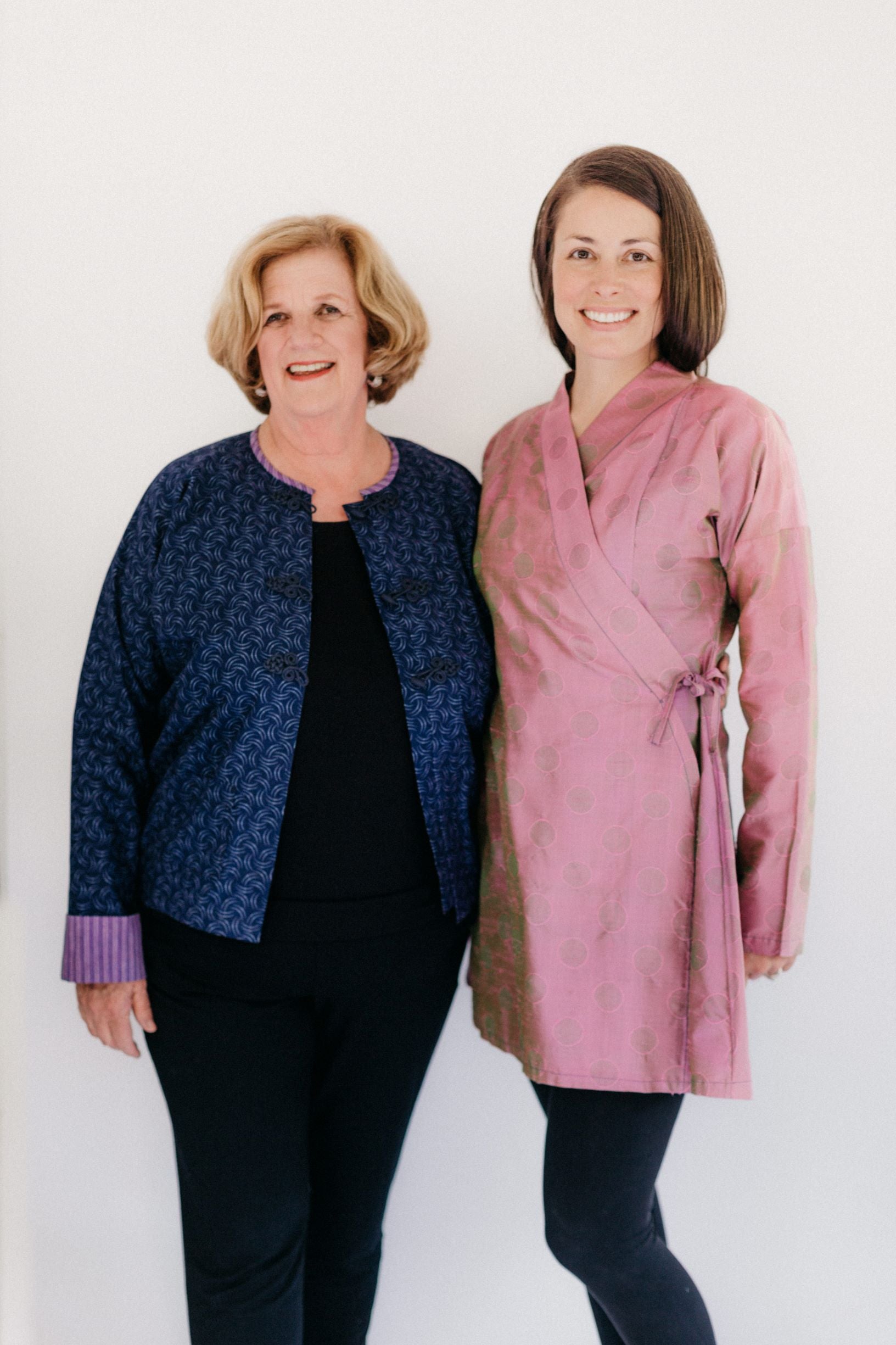 Two women modeling the Burmese Jacket (on left) and the Thai Blouse (right).  Burmese Jacket is unbuttoned in front and Thai Jacket is a lengthened adaptation.