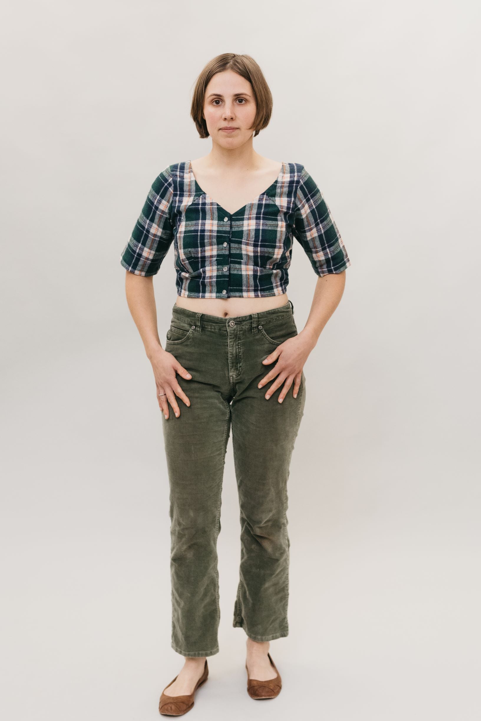 Photo of front view of Indian Choli top.  Model wears pants and stands in front of white backdrop.