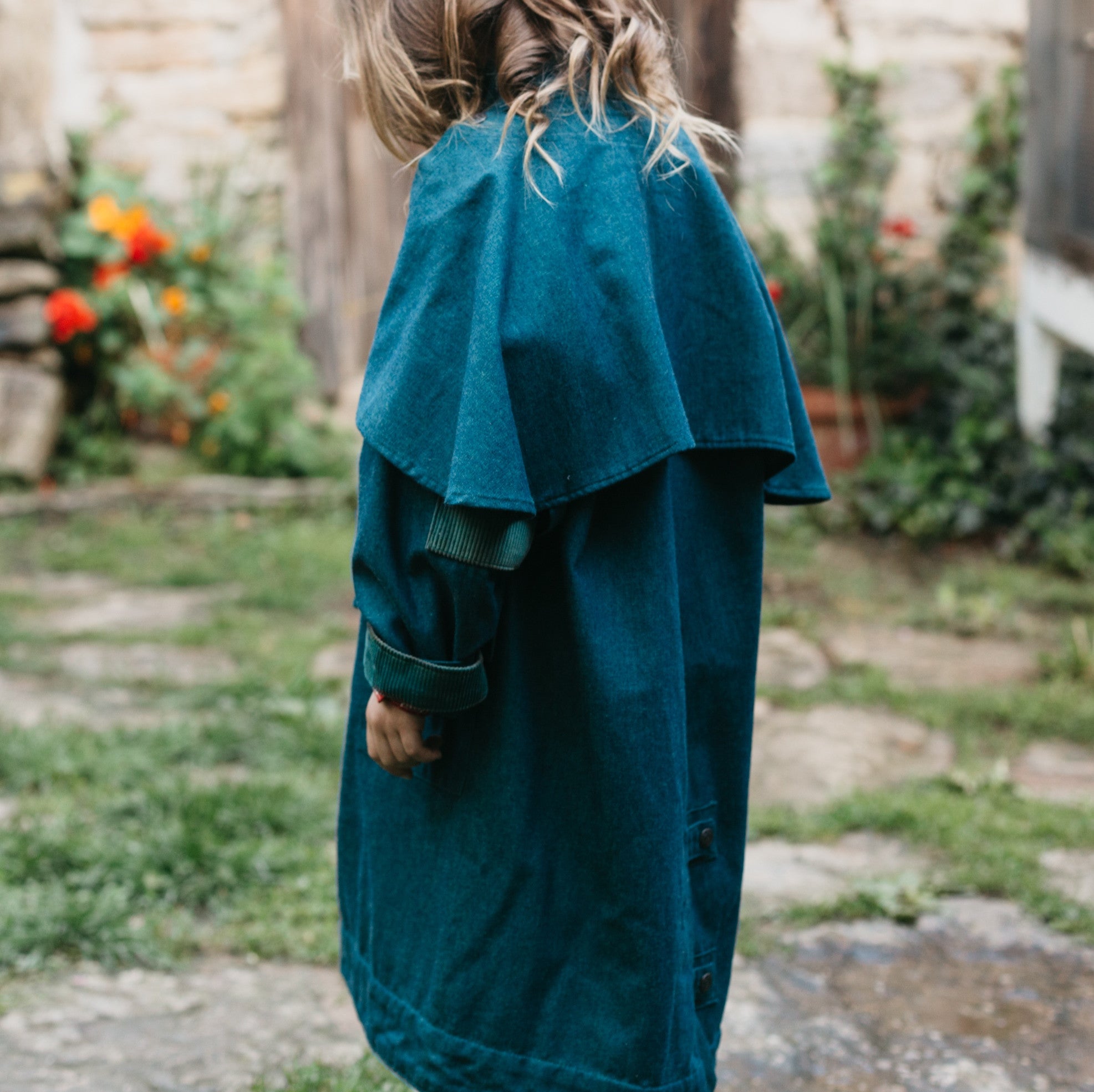 Young girl wearing a blue Australian Drovers Coat. side and back views