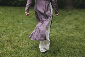 Photo of close up of lower portion of tunic and pants.  Woman is walking and tunic is flowing up with movement showing pants under and slit opening of tunic to the waist.