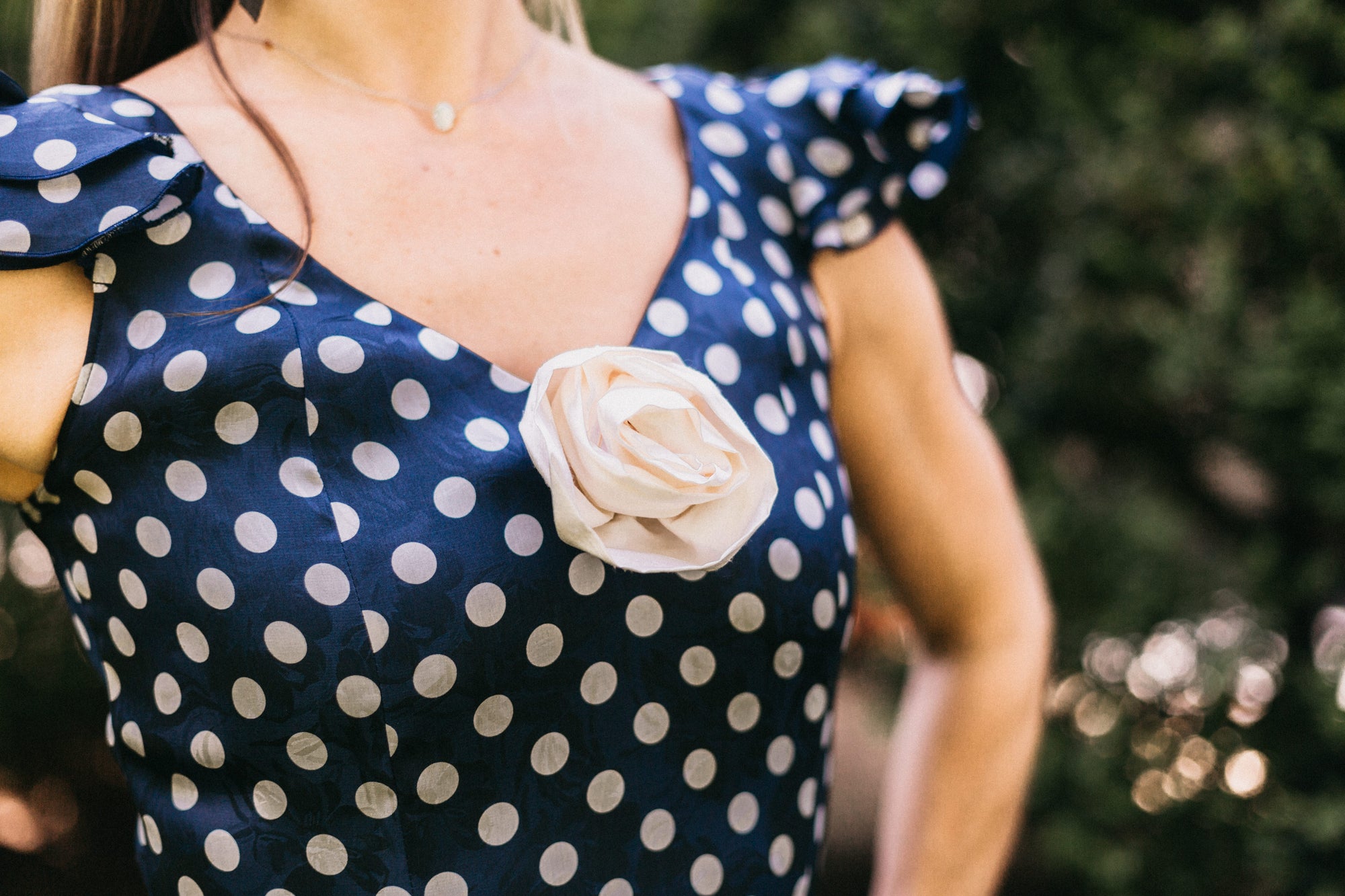 Close up photo of the neckline and rosette on the front of the dress.  Photo shows cap sleeves and front seams of the bodice of the dress.