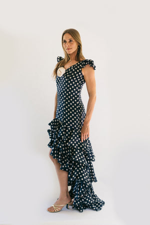 Woman standing in front of white studio backdrop wearing Dark Blue with white polka dots140 Flamenco Dress.  Woman stands with her arms by her side and is slightly turned to the right.