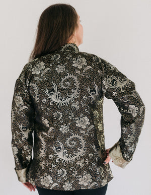 Back view of a woman wearing  Chinese Pajama Jacket with hand on her hip.