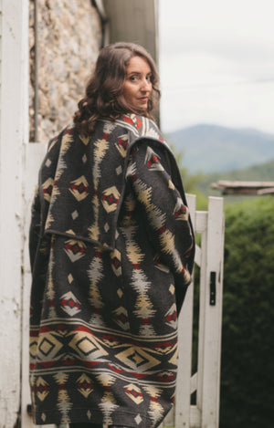 Photo of woman wearing view b of Hungarian Szur.  woman is walking and looking back over her shoulder.  Picture shows back collar lapel extending over shoulder to front of jacket.