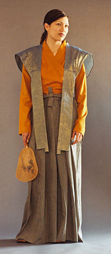 Photo of woman wearing Hakama pants with Kataginu.  Woman is holding a fan in her right hand.