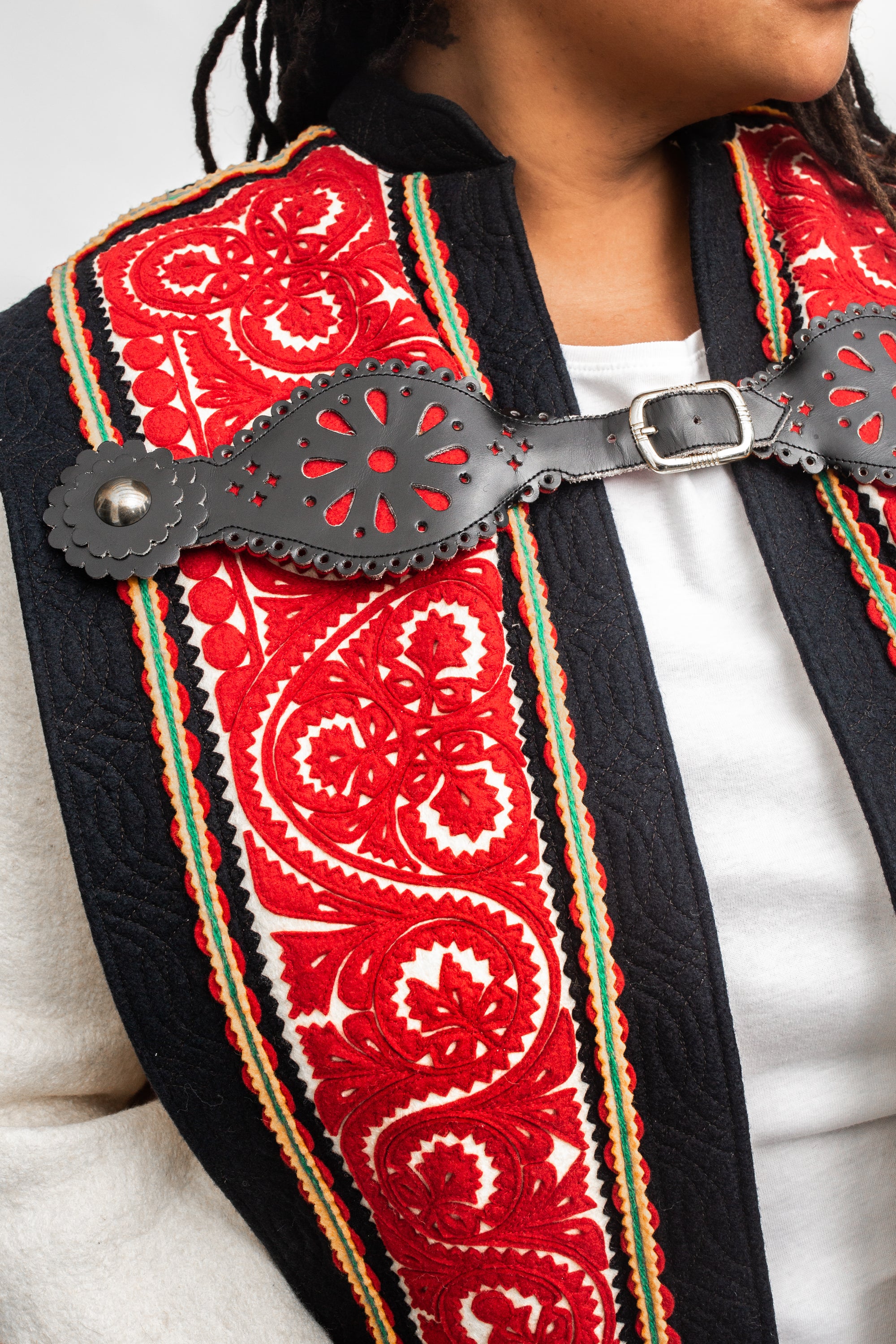 Close up of the cut feltwork of the szur - black, red, and white.  With the decorative leather buckle.