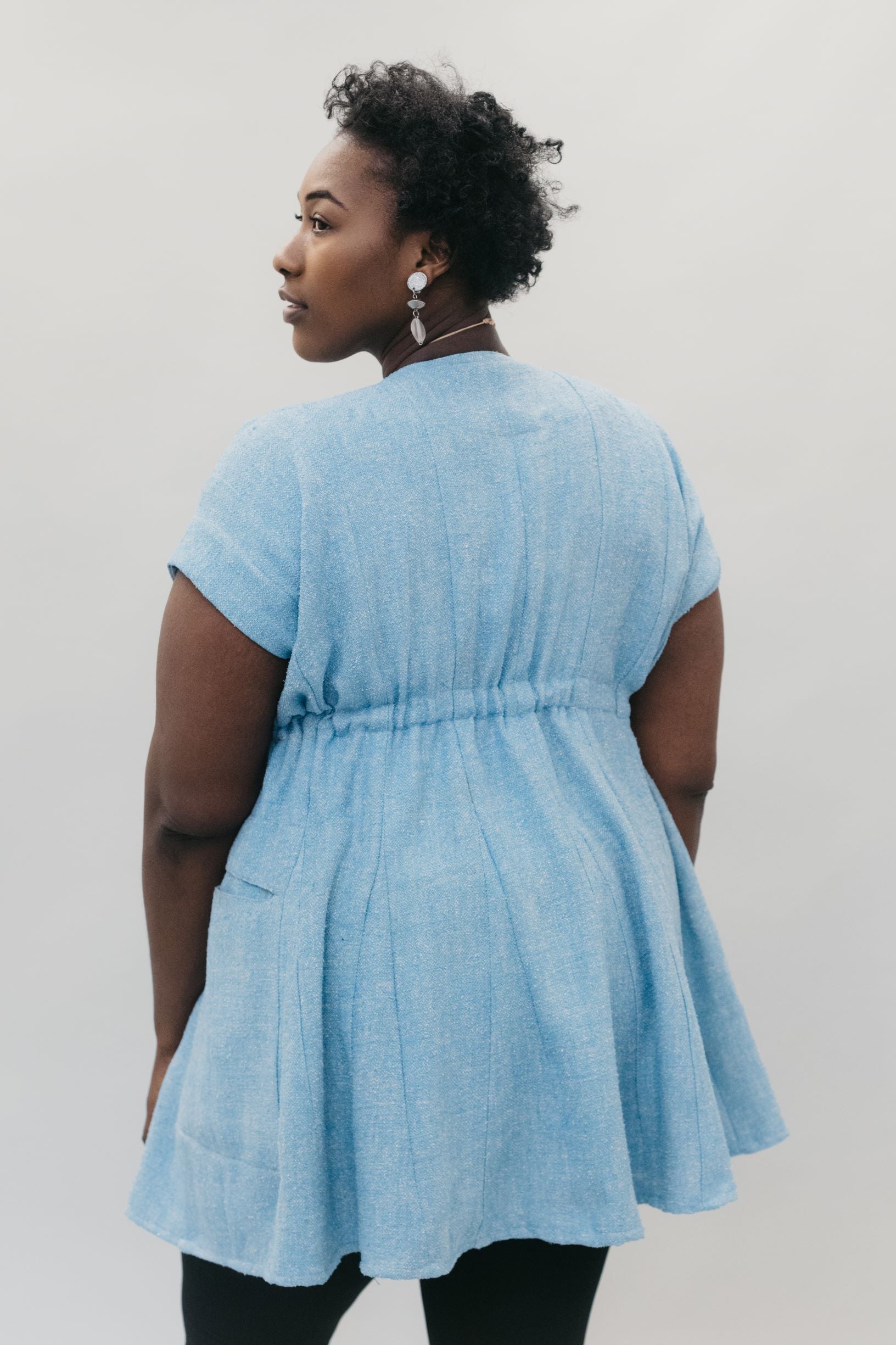 Back view of young African American woman with head looking over her shoulder wearing the women's Ghanaian Smock. 