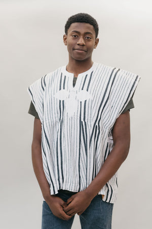 Front view of young African American man standing in front of a white studio backdrop wearing the men's Ghanaian Smock