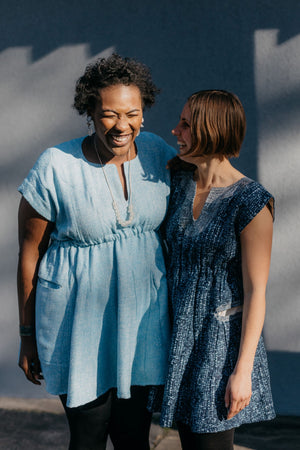 Two women African American and White laughing together wearing the Ghanaian Smock.