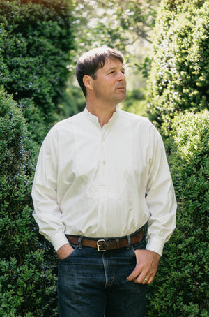 Man standing outside in victorian shirt tucked in and looking to the distance.