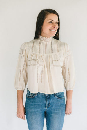 Brunette woman smiling, standing in front of a white studio backdrop wearing 206 Gibson Girl Blouse. 