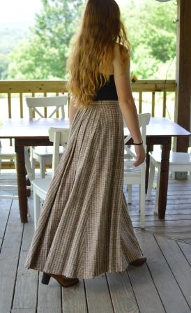 Back view of young red head woman walking in front of a dinning room table outside on a porch wearing black spaghetti strapped top wearing 209 Walking Skirt.