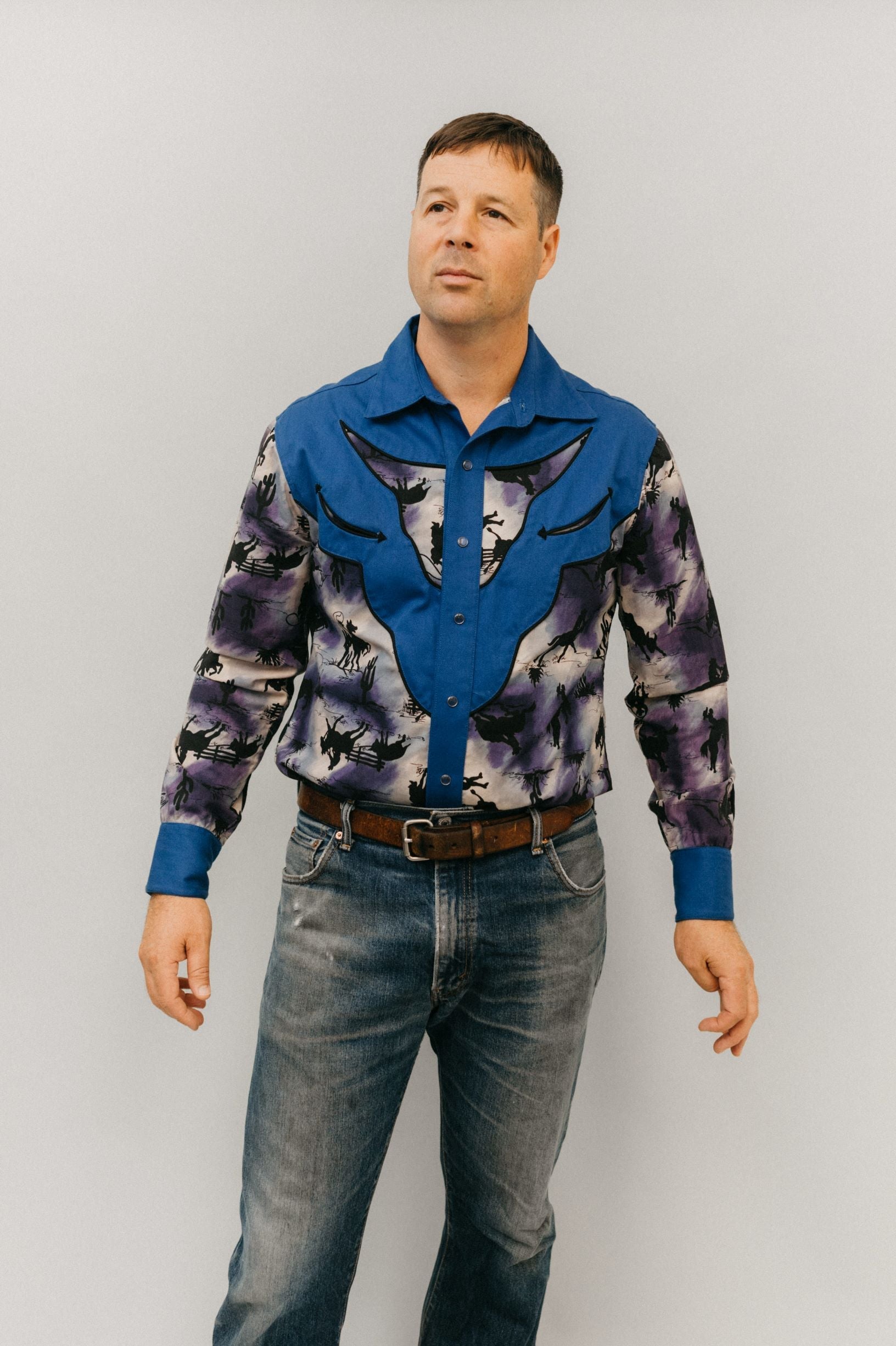 Man standing in front of a white studio backdrop, wearing 212 Five Frontier Shirt with decorative bull's head yoke.