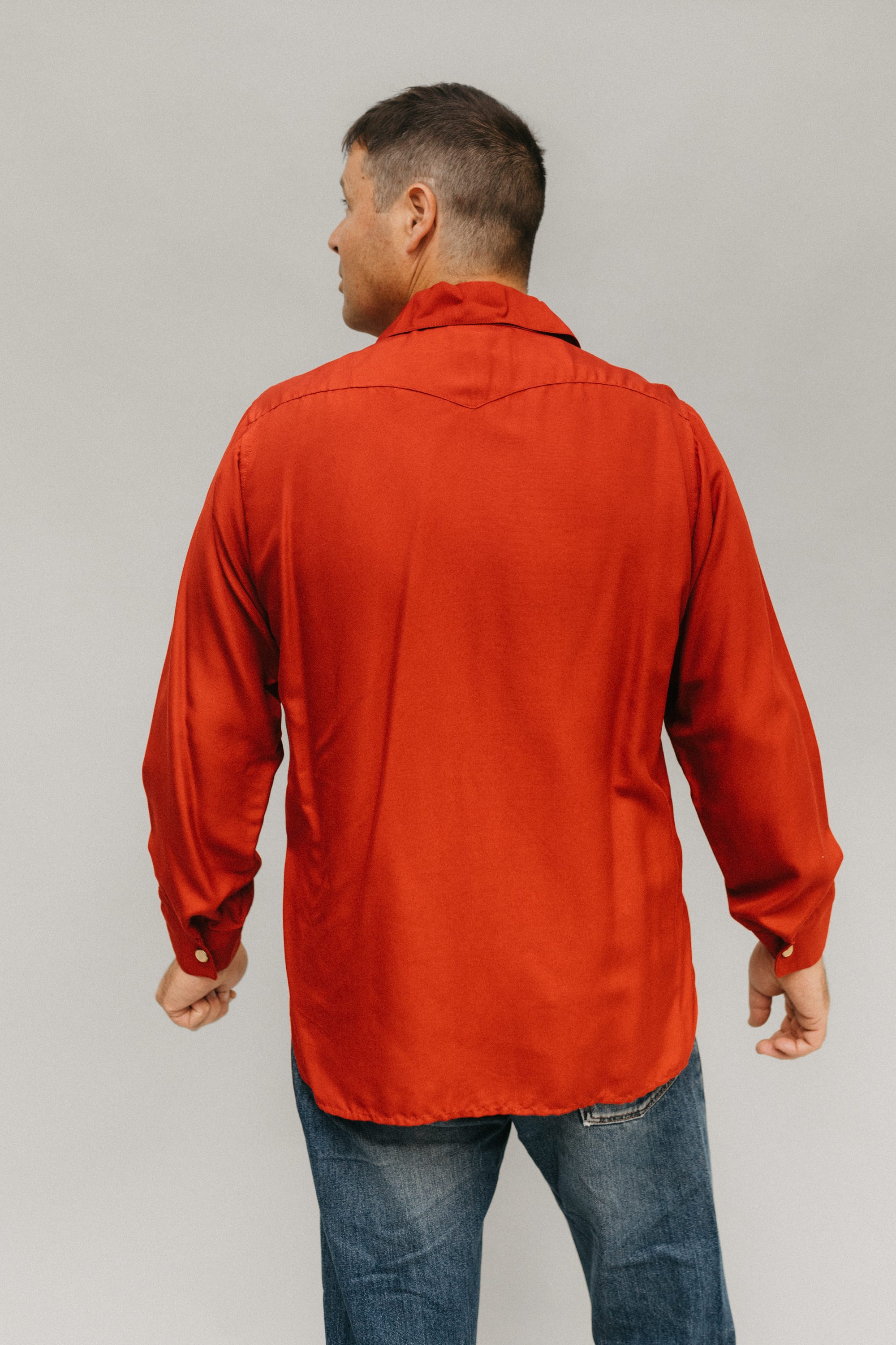 Back view of man standing looking to the left in front of a white studio backdrop wearing 212 Five Frontier Shirts.