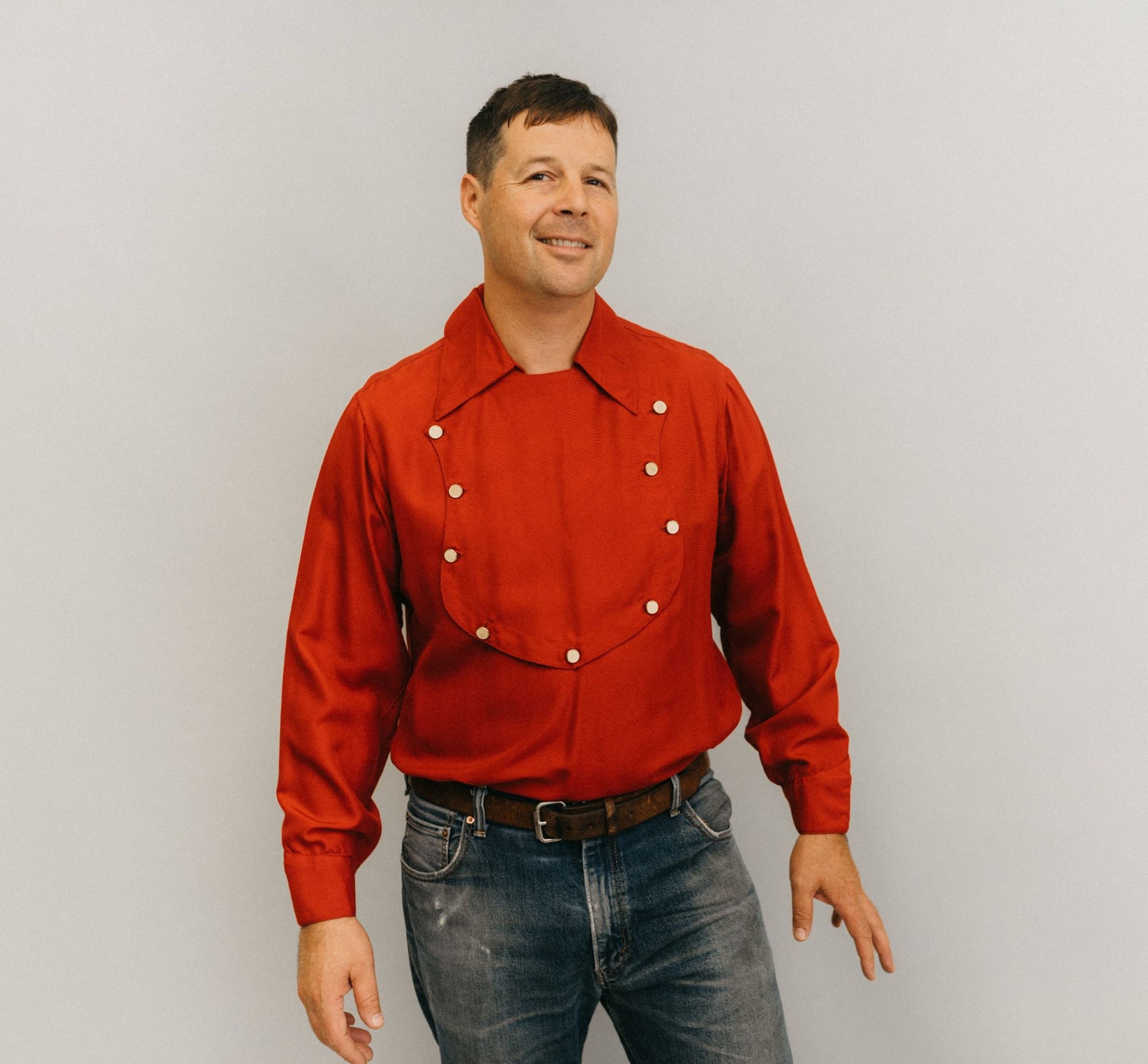 Man standing in front of a white studio backdrop wearing 212 Five Frontier Shirts View C with a buttoned bib shape in the front. 