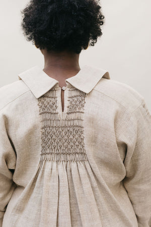 Close up back view of African American woman wearing 221 English Smock Frock, that is smocked in the back.