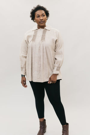 Young African American woman standing in front of a white studio backdrop looking right, wearing 221 English Smock. 