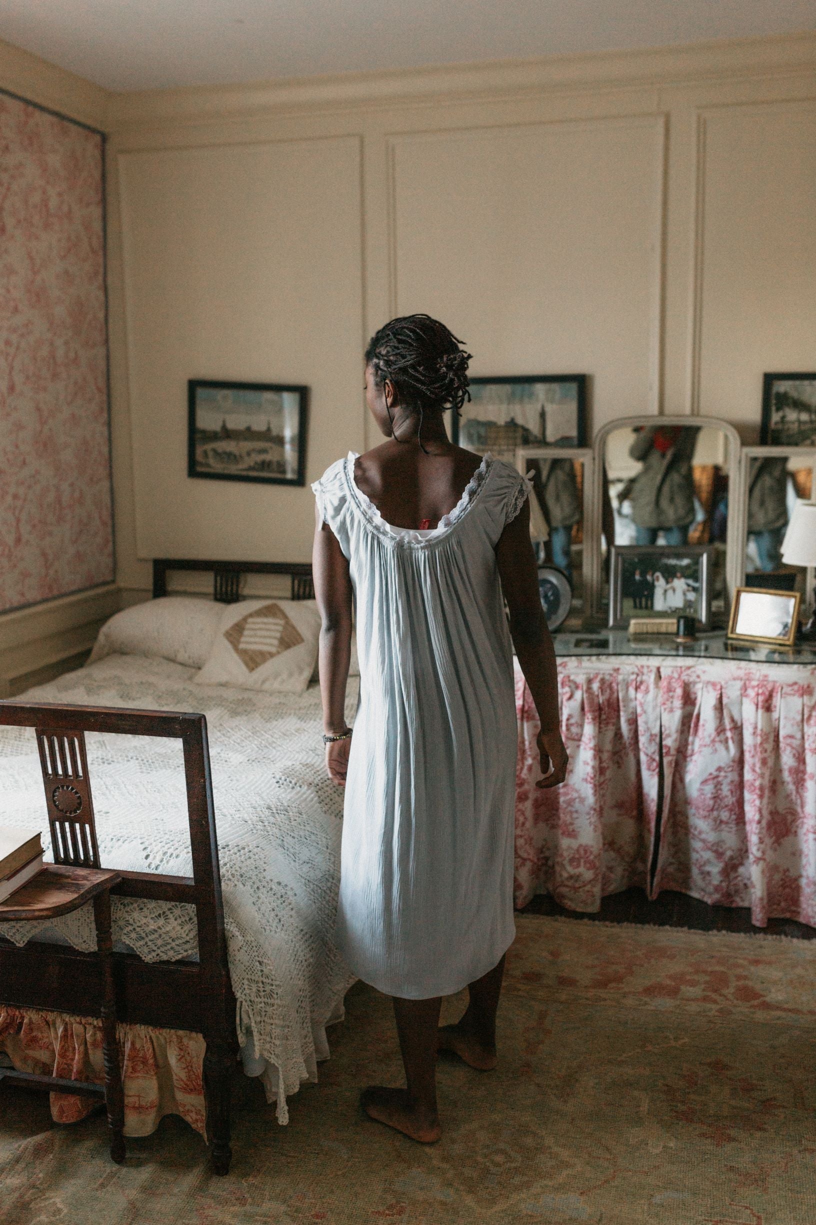 Back view of African women standing next to a bed wearing 223 A Lady's Chemise.