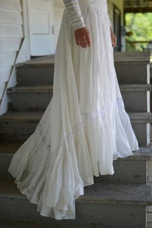 Close up of Woman standing on a stair case displaying the 227 Edwardian Bridal Gown and Dress full sweep of skirt.