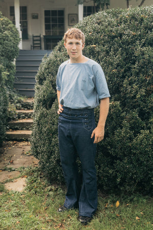 Young  male standing with hand on hip, surrounded by greenery wearing 229 Sailor pants.