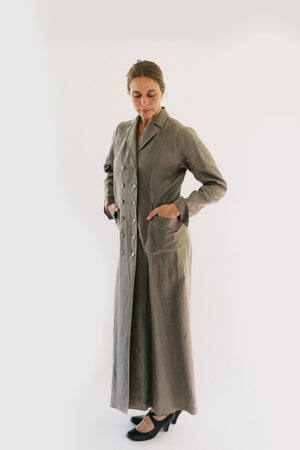 Woman wearing standing in front of a white studio backdrop looking down with hands in pockets wearing 230 Model T Duster