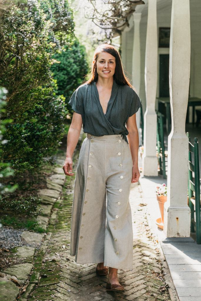Young brunette white woman walking surrounded by greenery wearing the 231 Big Sky Riding skirt buttoned giving the effect of pants.