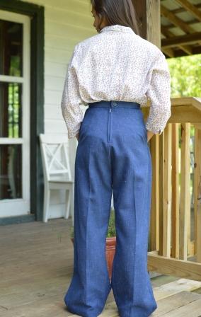 Back view of a young girl wearing the 240 Rosie the Riveter slacks and shirt, standing on a porch.