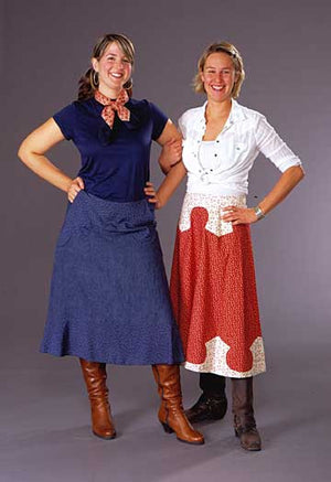 Two young white women smiling and standing with hands on hips in front of a grey studio backdrop wearing the 243 Rodeo Cowgirl skirt.