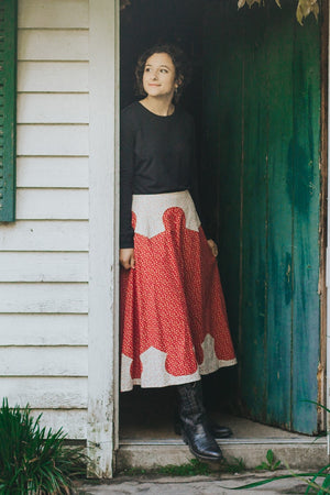 Young brunette white woman standing in a doorway looking to her left wearing 243 Rodeo Cowgirl skirt and black boots