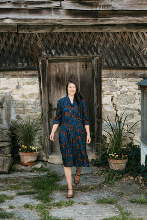 woman walking on a stone pathway in front of a old wooden door wearing 247 Lindy Shirtdress.