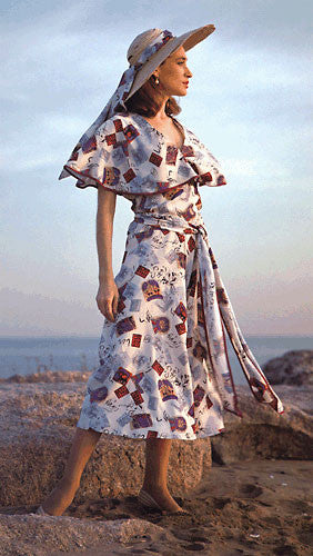 Photo of woman in shin length beach pyjamas.  Standing on rocks with ocean behind her.  wearing large hat with sash.