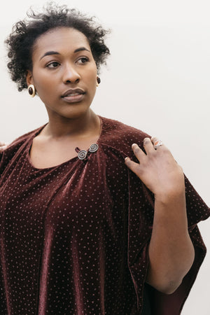 African American woman with short black hair gazing to the right with left hand on her shoulder wearing the Monte Carlo Dress V-neck Tunic