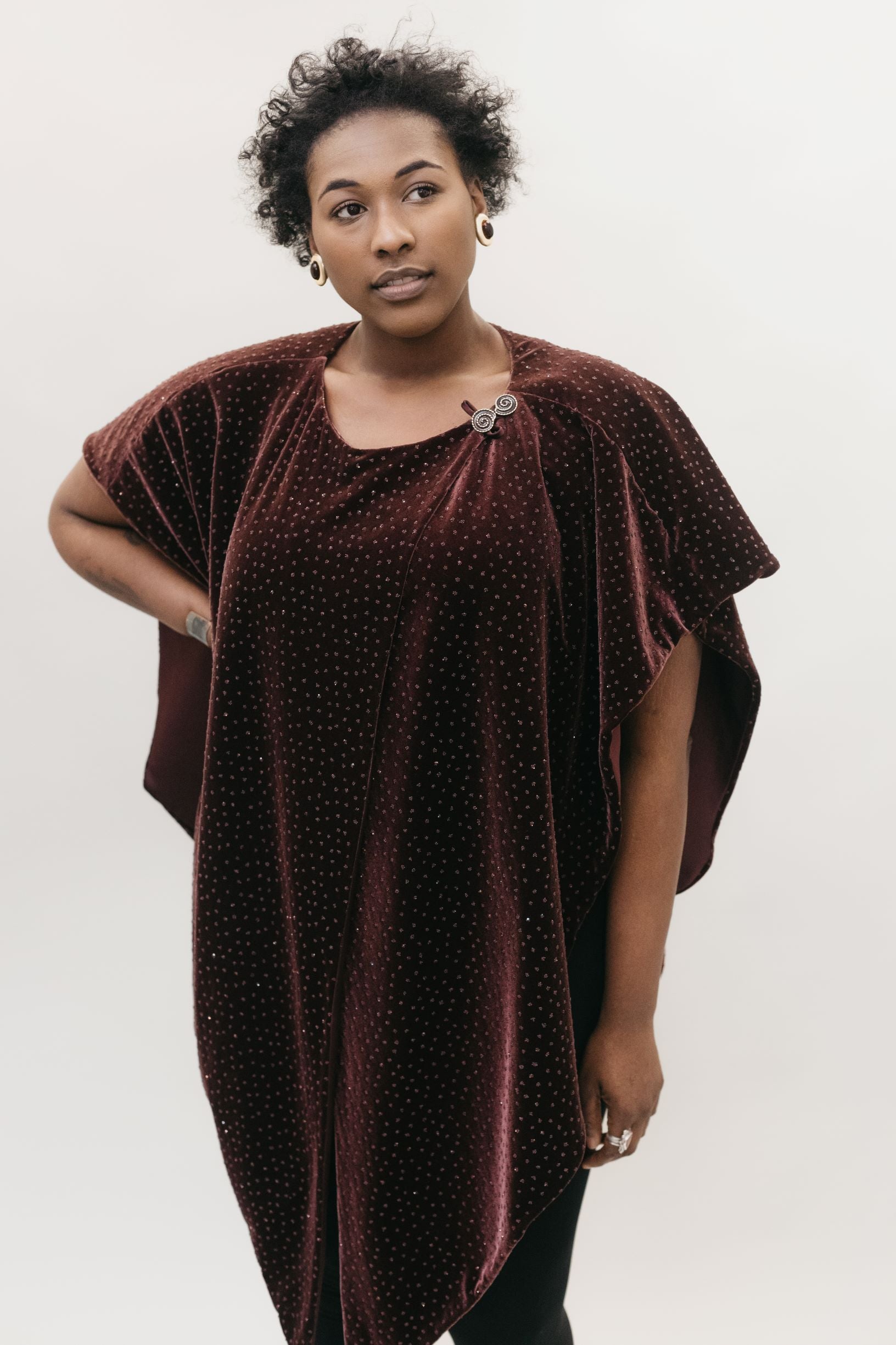 African American woman gazing to the right with her right hand on her hip standing in front of a white studio backdrop wearing the Monte Carlo Dress V-Neck Tunic