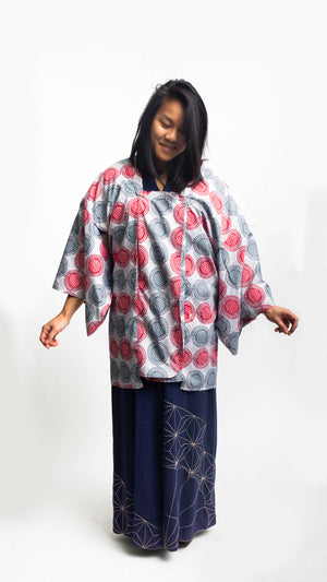 Woman wearing a red and grey spiral printed ankara fabric made into a Michiyuki over a blue cotton kimono
