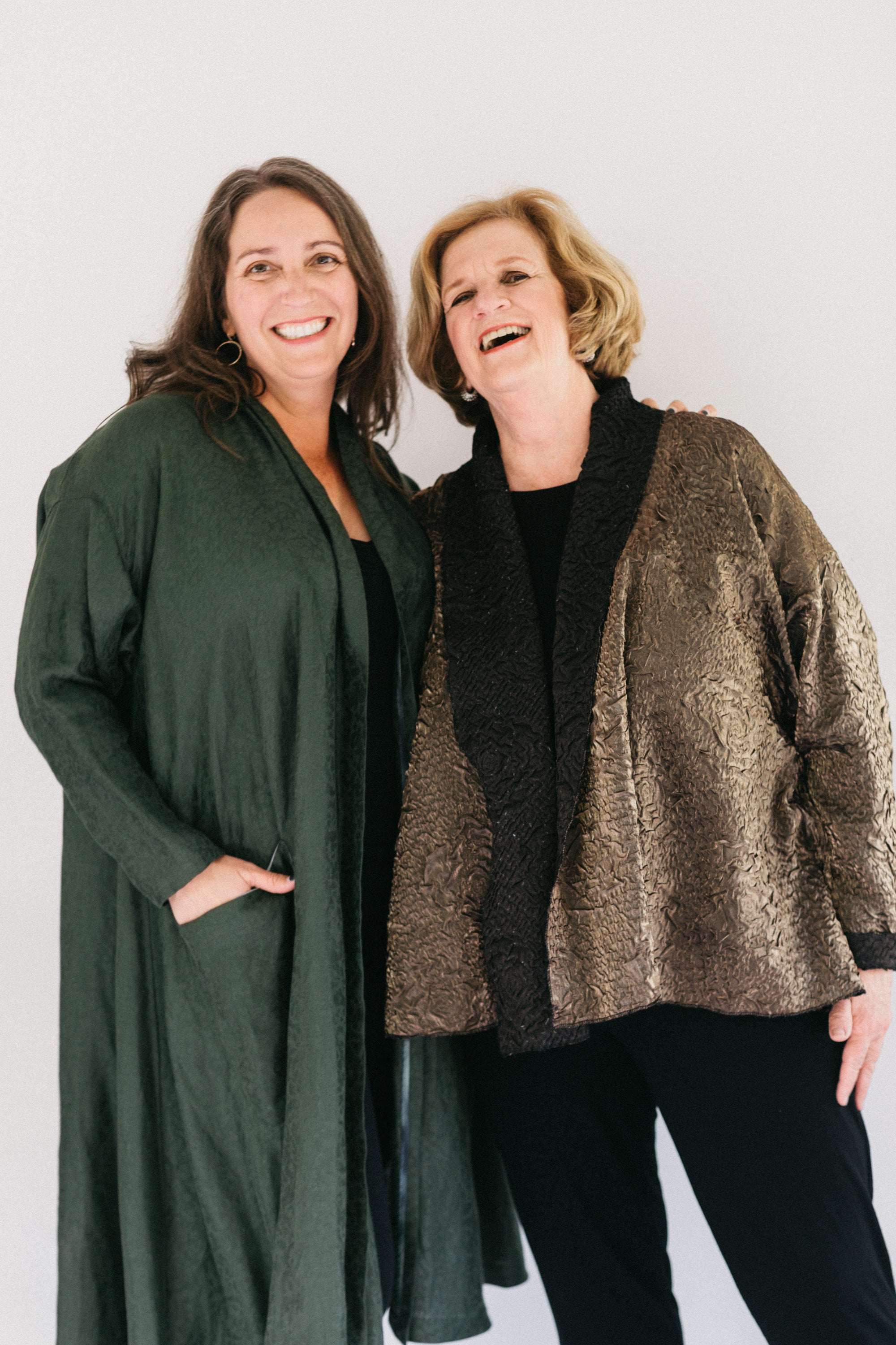 Two women  smiling standing next to each other wearing the 254 Swing Coat one long and the other hip length.