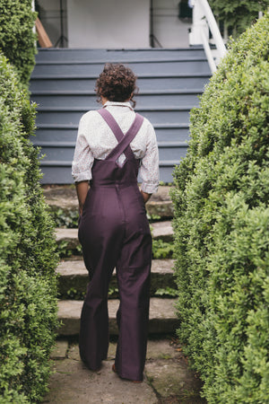 Back view of young woman walking wearing the 240 Rosie the Riveter Overalls. 