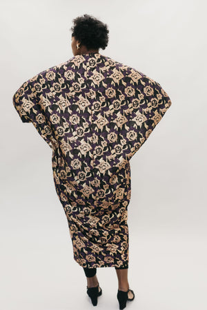 African American woman standing in front of a studio white backdrop, Back view of Poiret Cocoon Coat